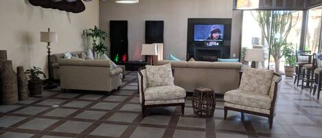 A spacious living room with a large sofa set, a television, and a fireplace.