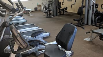 Un gimnasio con cintas de correr, una máquina de remo y equipo de levantamiento de pesas.