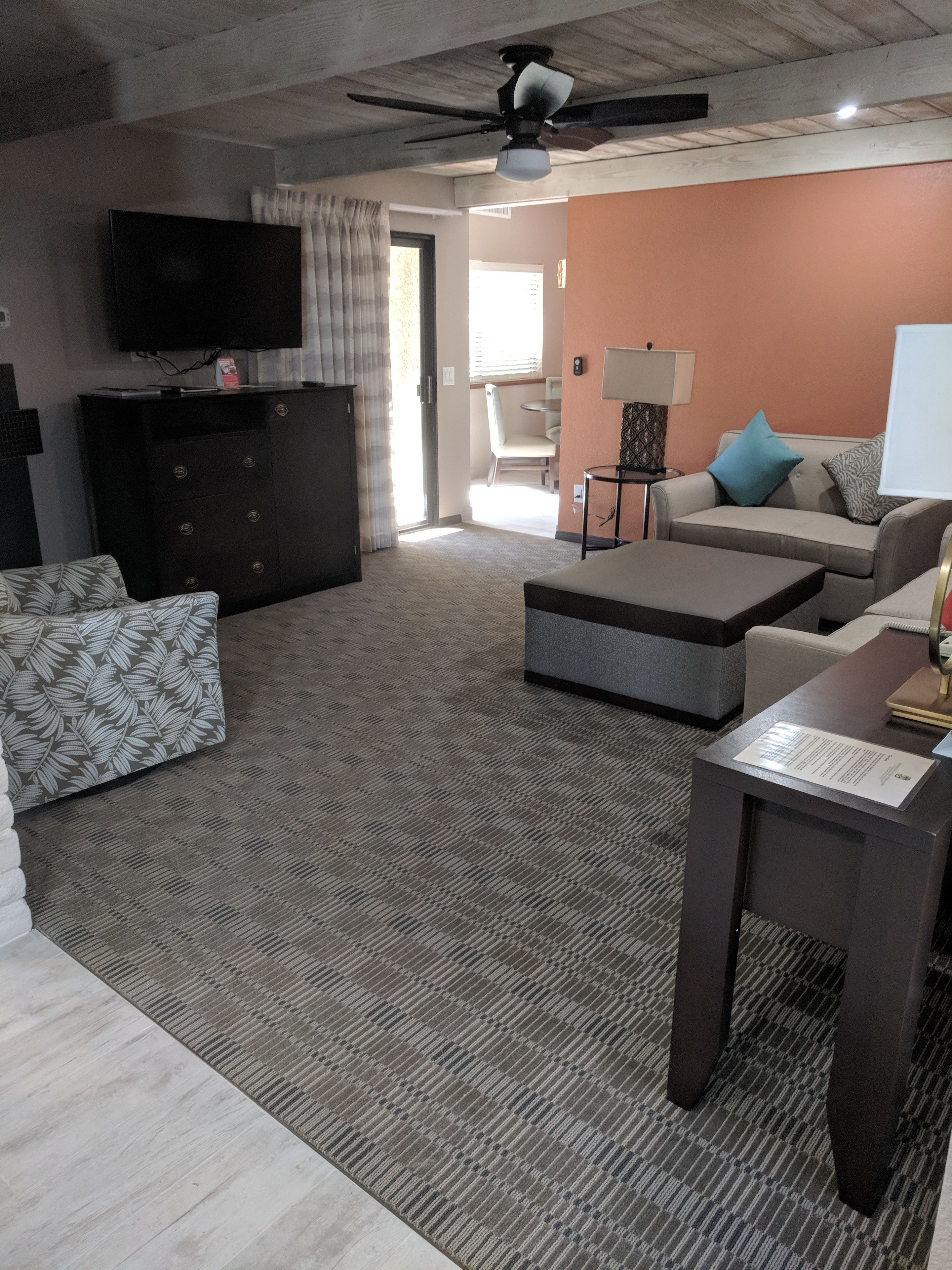 A living room with a sofa, a coffee table, a TV, and a ceiling fan.
