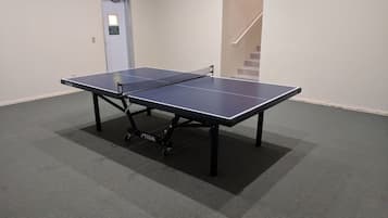 A ping pong table in a room with carpeted flooring and a door with a sign.