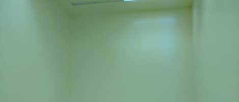 A spacious room with a wooden floor and white walls, equipped with ceiling lights.