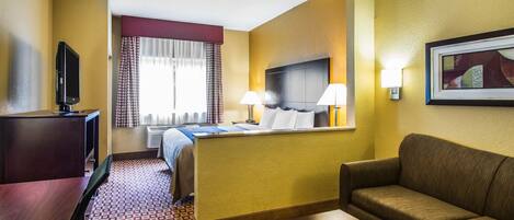 A hotel room with a bed, a desk, a television, a sofa, and a painting on the wall.