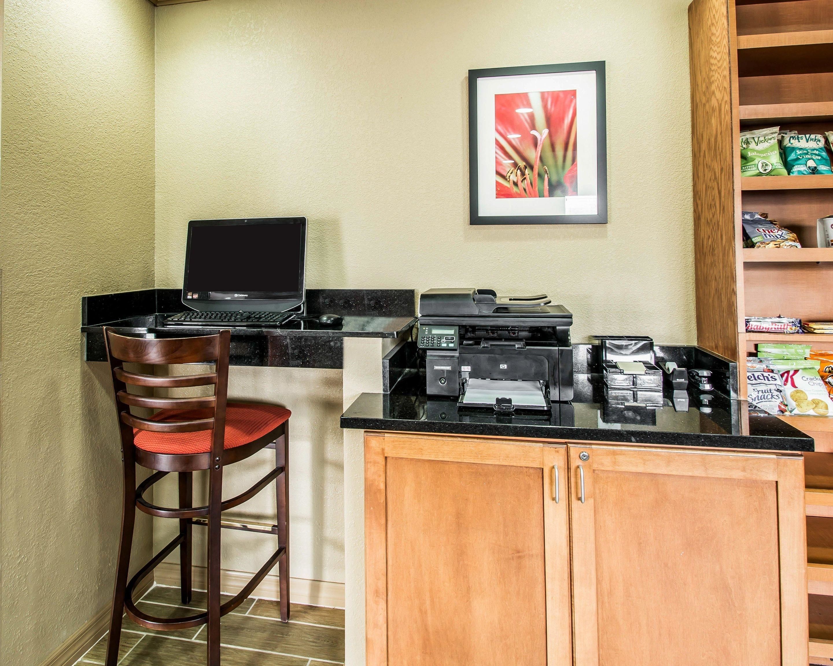 A kitchenette with a laptop, printer, and a small bar stool.