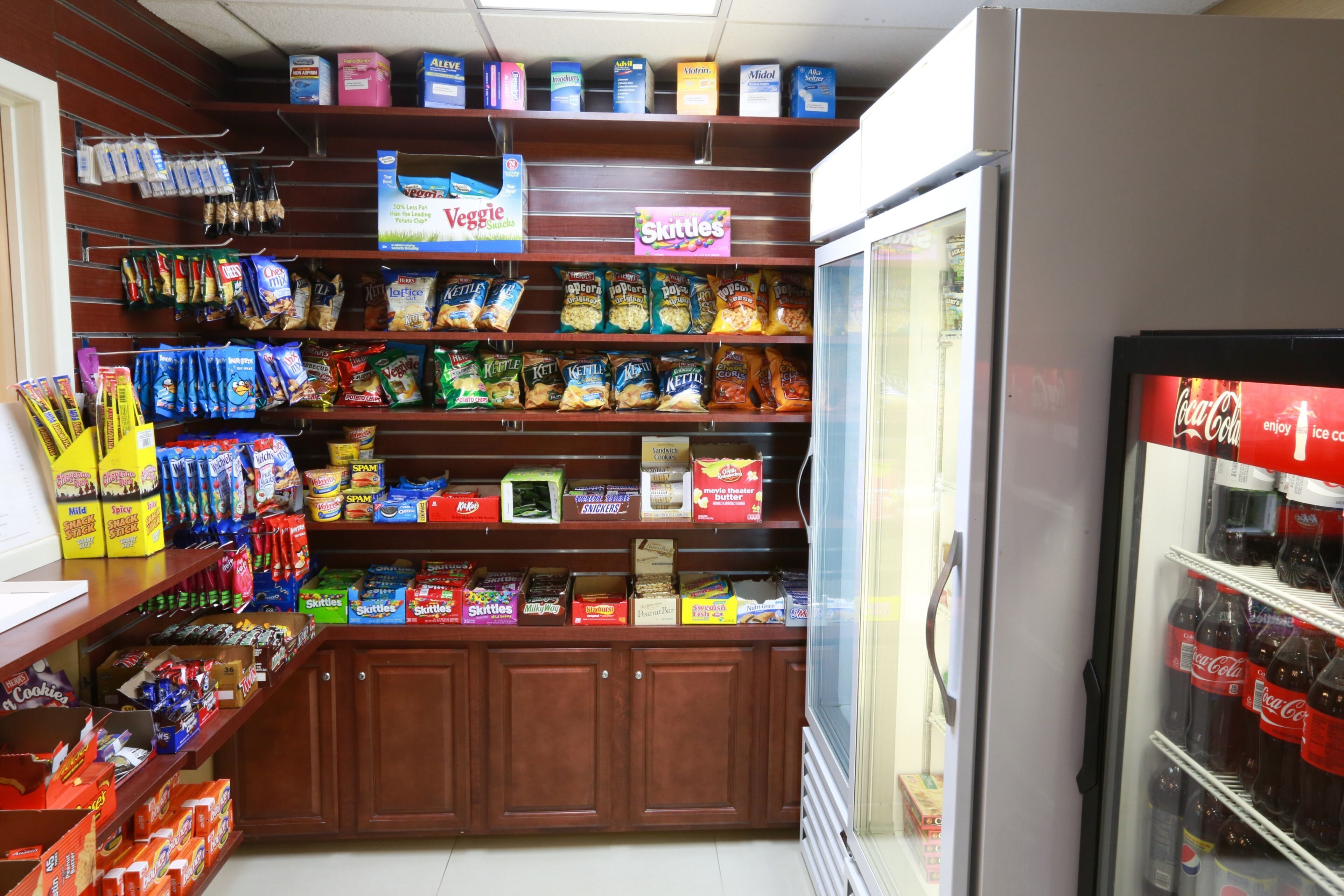 A snack and beverage vending area with various snacks, including chips and candy, and a refrigerator stocked with beverages.