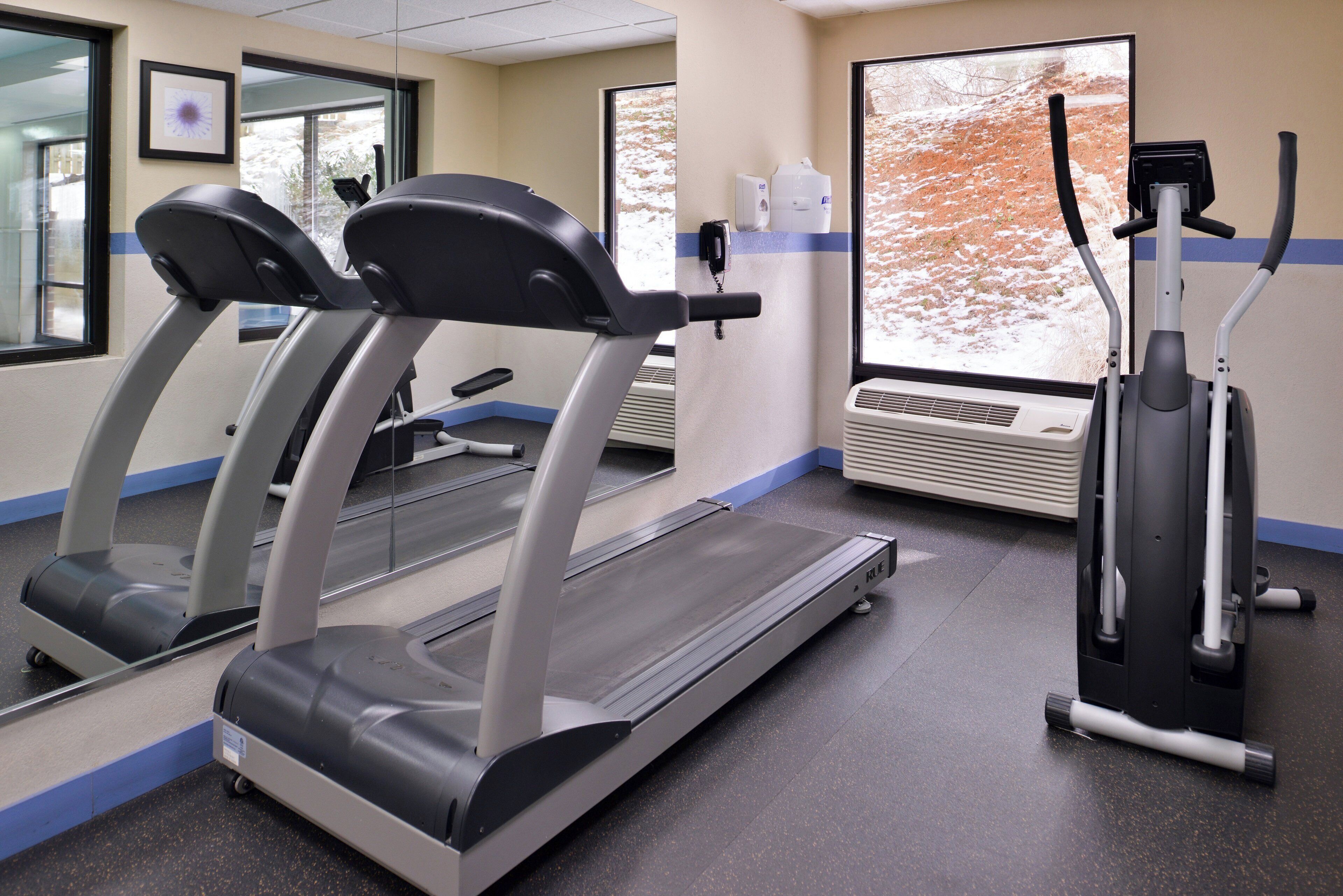 Un centre de remise en forme équipé de tapis de course, d’un appareil elliptique et d’un distributeur d’eau.