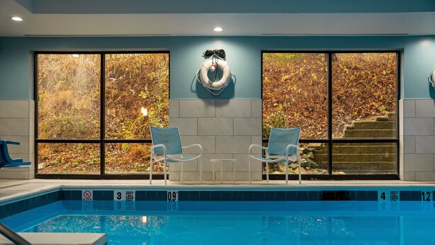 A swimming pool with two chairs and a lifebuoy on the wall. - Holiday Inn Express Hotel & Suites West Chester by IHG (West Chester)