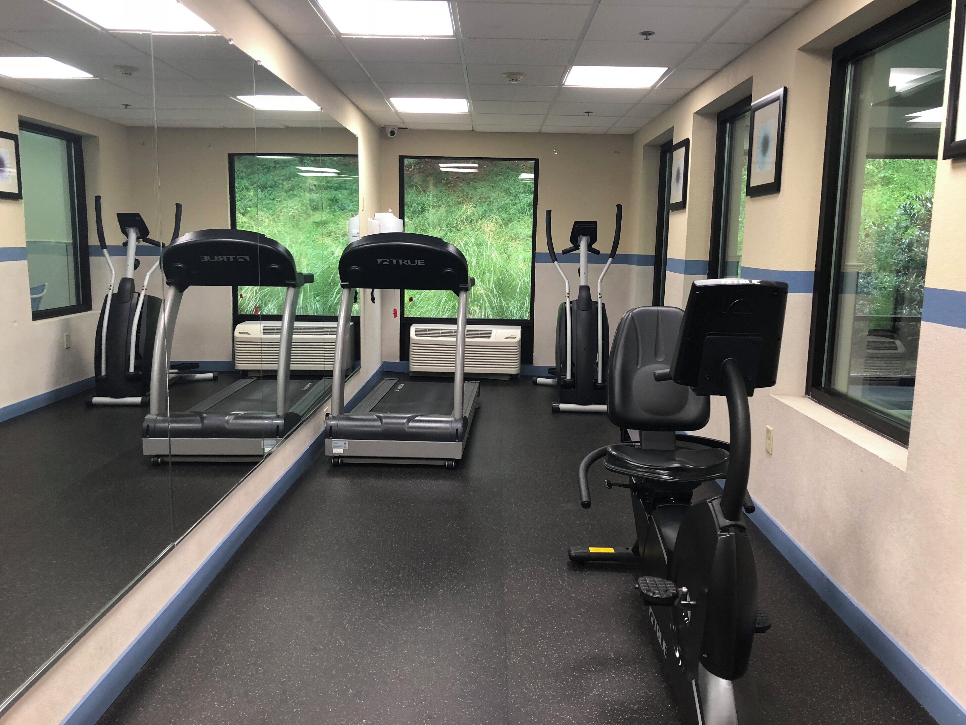 Un gimnasio con cintas de correr, una elíptica y una bicicleta estática.