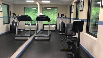 Un gimnasio con cintas de correr, una elíptica y una bicicleta estática.