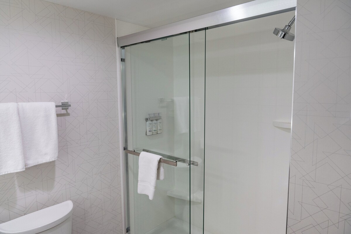 Uma casa de banho moderna com chuveiro em cabine de vidro, sanita e um porta-toalhas.