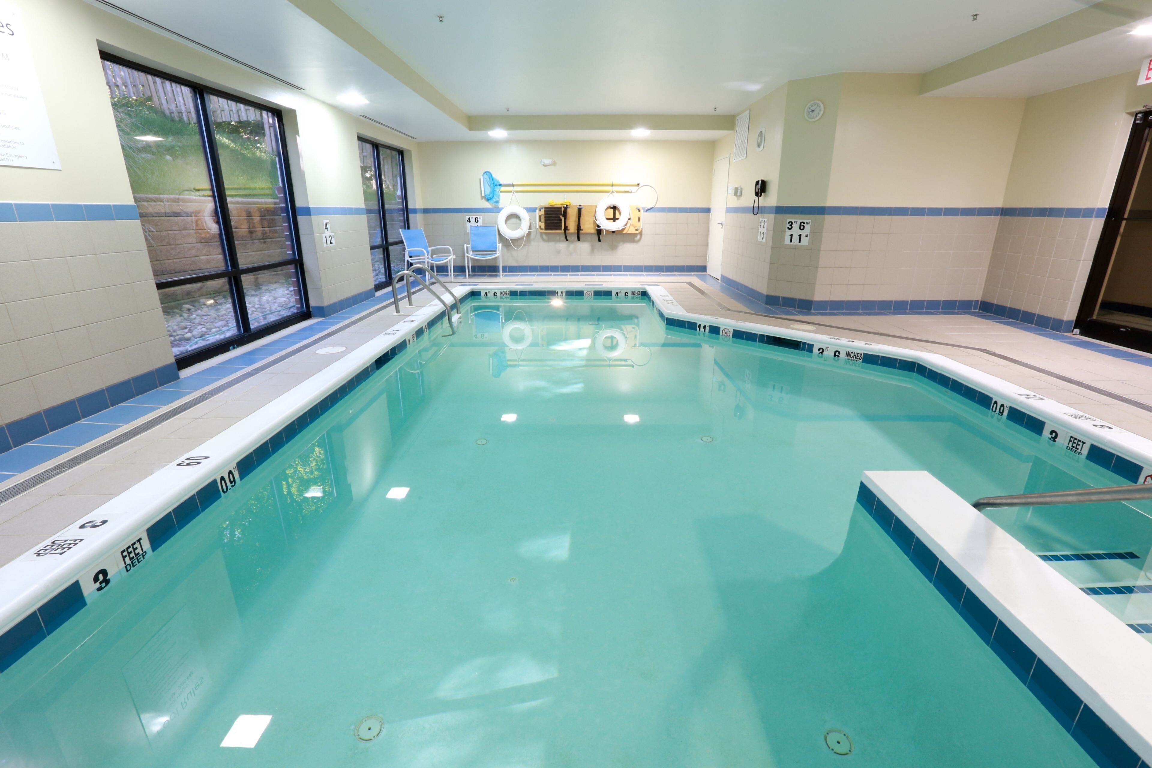 Una piscina con agua cristalina, marcas de profundidad y una silla de salvavidas.