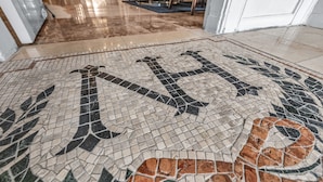 A detailed mosaic floor with a large 'H' and leaf patterns.