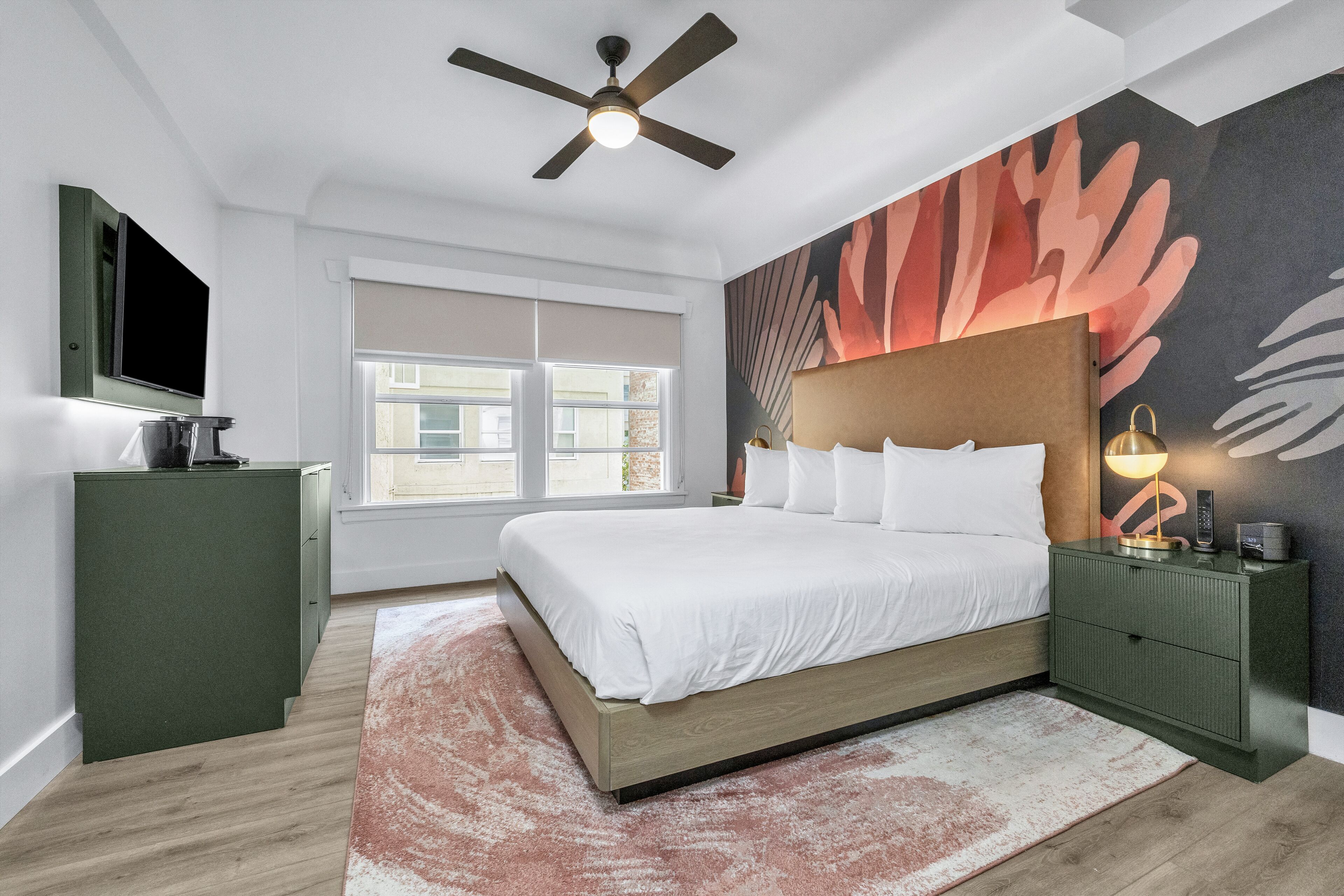 Un dormitorio moderno con cama, mesita de noche, televisor y ventilador de techo.