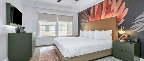 Un dormitorio moderno con cama, mesita de noche, televisor y ventilador de techo.
