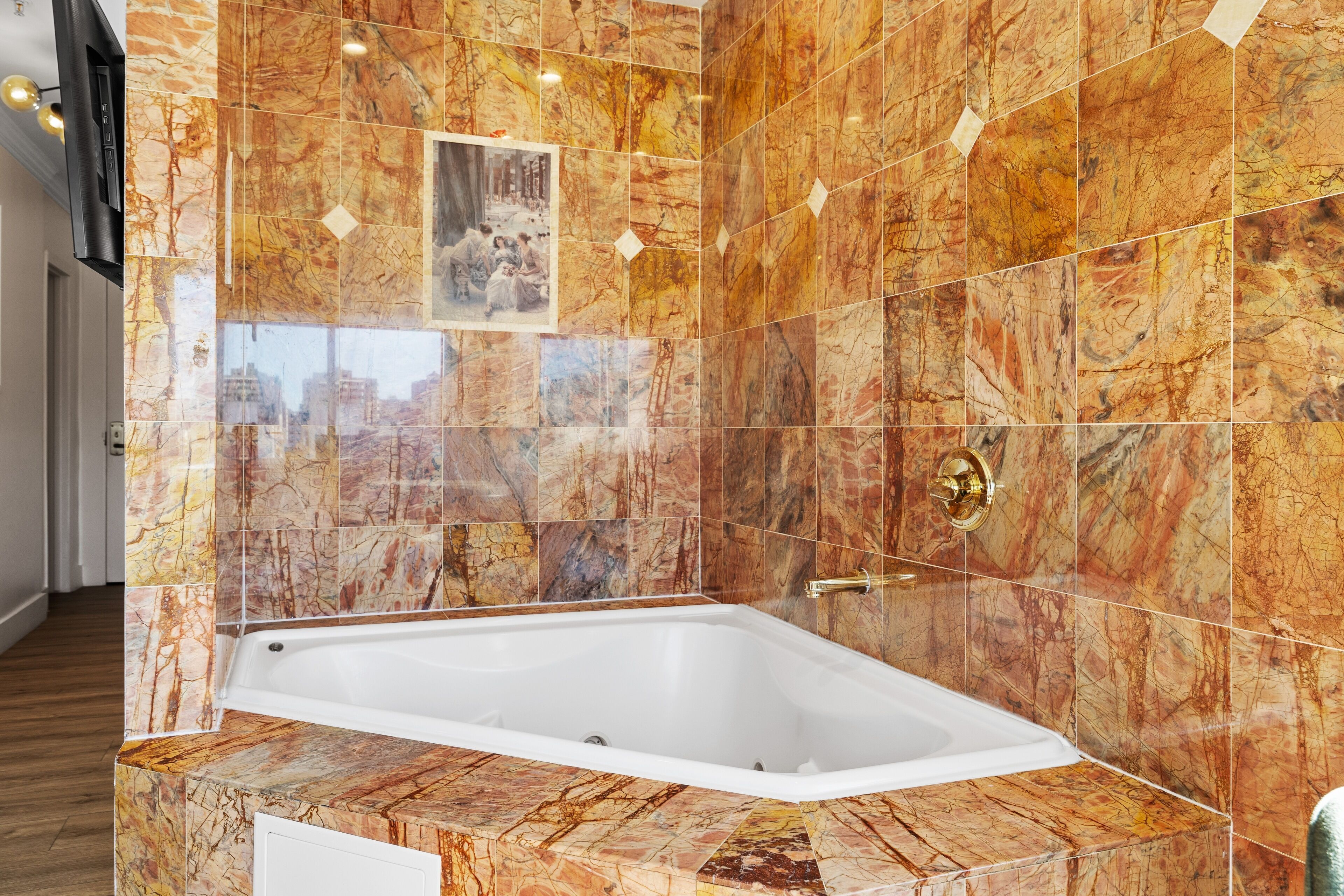 A modern bathroom with a marble tile wall, a bathtub, and a framed picture.