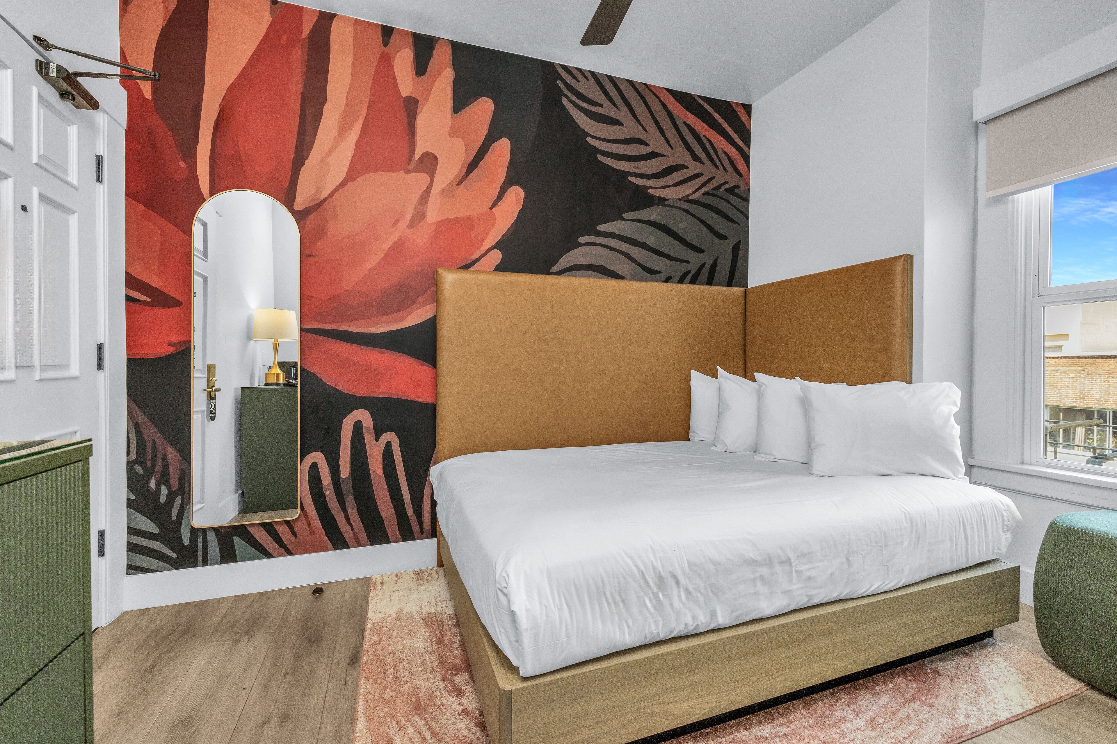 Una camera da letto moderna con un letto grande, uno specchio a parete e una finestra con vista.