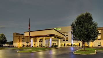 Edifício Holiday Inn Express com telhado plano, grandes janelas e mastro com bandeira.