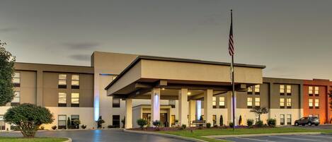 A modern building with a flat roof, large windows, and a flagpole with an American flag.