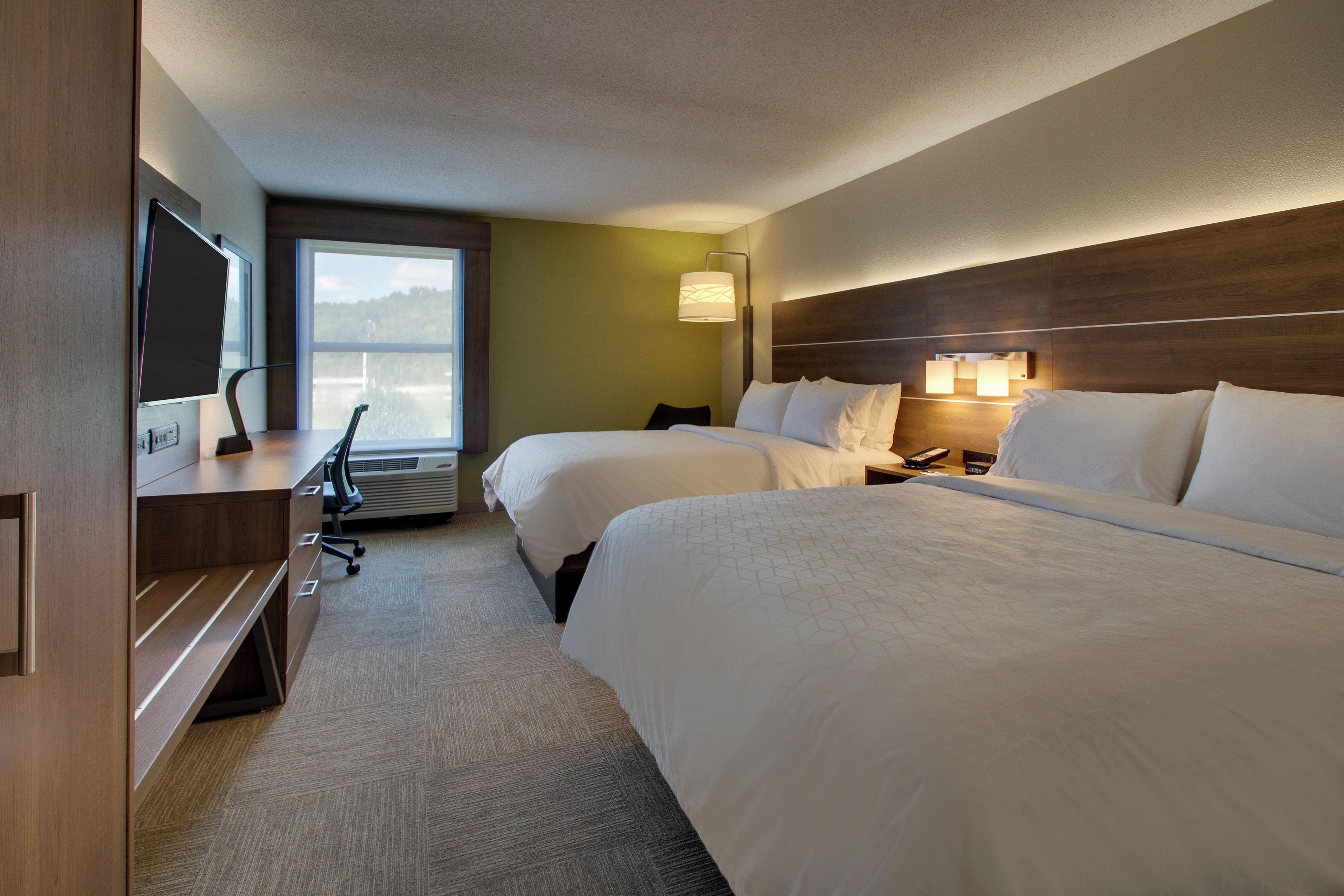 Habitación de hotel con dos camas, un escritorio con silla, televisión y ventana con vistas.