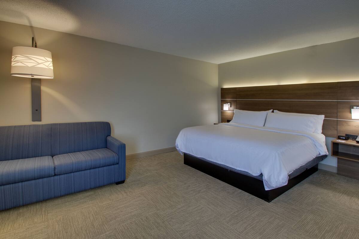 Ein Hotelzimmer mit Bett, einer Couch und einem Nachttisch mit Lampe.