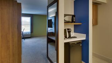 Ein Hotelzimmer mit Holztür, einer Mikrowelle, einer Kaffeemaschine und einem kleinen Waschbecken.