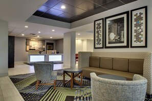 Een moderne lobby met een bank, stoelen en kunstwerken aan de muur.