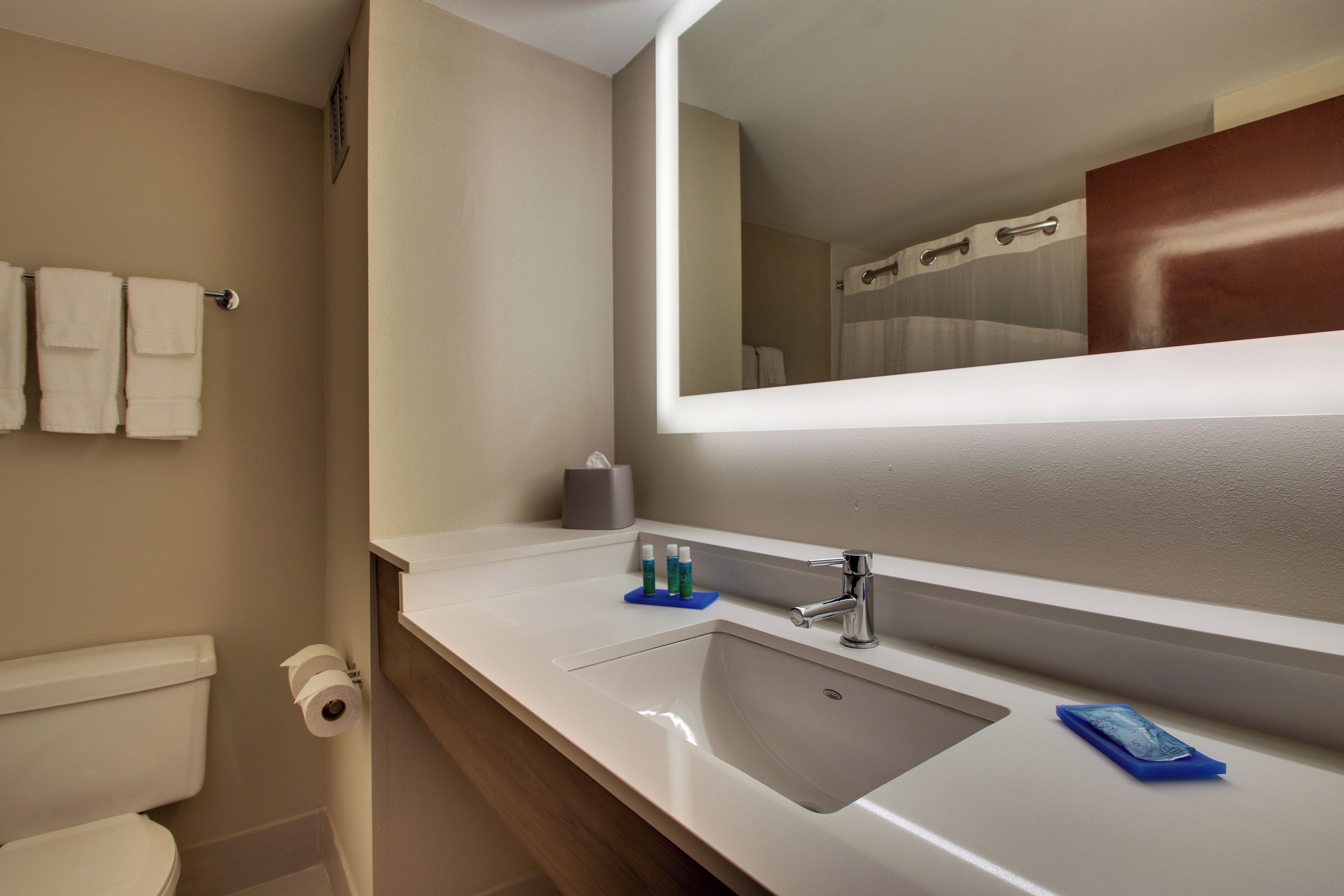 A bathroom with a toilet, sink, and mirror.