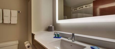 A bathroom with a toilet, sink, and mirror.