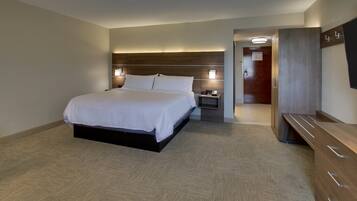 A modern hotel room with a large bed, bedside tables, a wardrobe, and a desk.