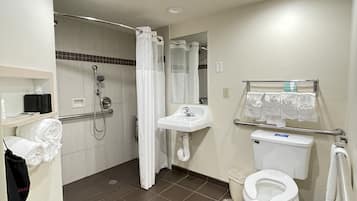 Un baño con ducha, inodoro, lavabo y barras de apoyo.