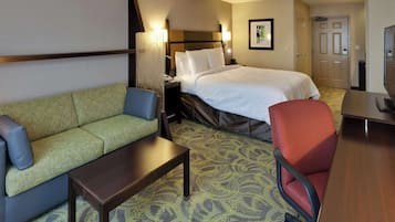 Une chambre d’hôtel comprenant un lit, un canapé, une chaise, un bureau et une table de chevet.