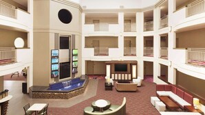 Un vaste atrium doté d’une piscine centrale, de nombreux balcons et d’un coin salon avec un téléviseur à écran plat.