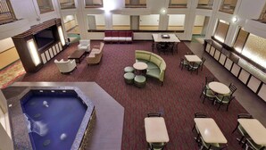 Un hall d’hôtel doté d’une piscine, de coins salon et d’un bar.