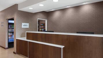 A reception area with a wooden reception desk, a vending machine, and a sign for 'NABROST BONVOY'.