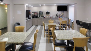 A restaurant with striped flooring, wooden chairs, and tables. There are vending machines and a flat-screen TV on the wall. - Quality Inn Mount Pleasant (Mount Pleasant)
