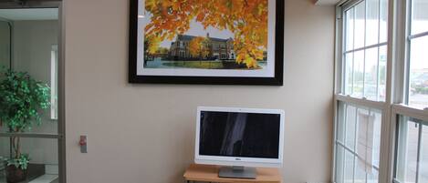 Een kamer met een bureau, een ingelijste foto aan de muur en een raam.