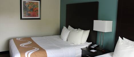 Habitación de hotel con dos camas, una mesita de noche con una lámpara, un teléfono y un cuadro en la pared.