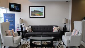 A modern living room with a dark sofa, two armchairs, a glass coffee table, and a framed picture on the wall. - Quality Inn Mount Pleasant (Mount Pleasant)