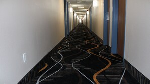 A long, narrow hallway with patterned carpet and blue doors on either side. - Quality Inn Mount Pleasant (Mount Pleasant)