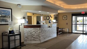 A reception area with a reception desk, a clock, framed artwork, and a door leading outside. - Comfort Inn & Suites Wilkes Barre - Arena (Wilkes-Barre)