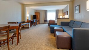 A hotel room with a dining table, chairs, a sofa, a TV, and a bed. - Comfort Inn & Suites Wilkes Barre - Arena (Wilkes-Barre)