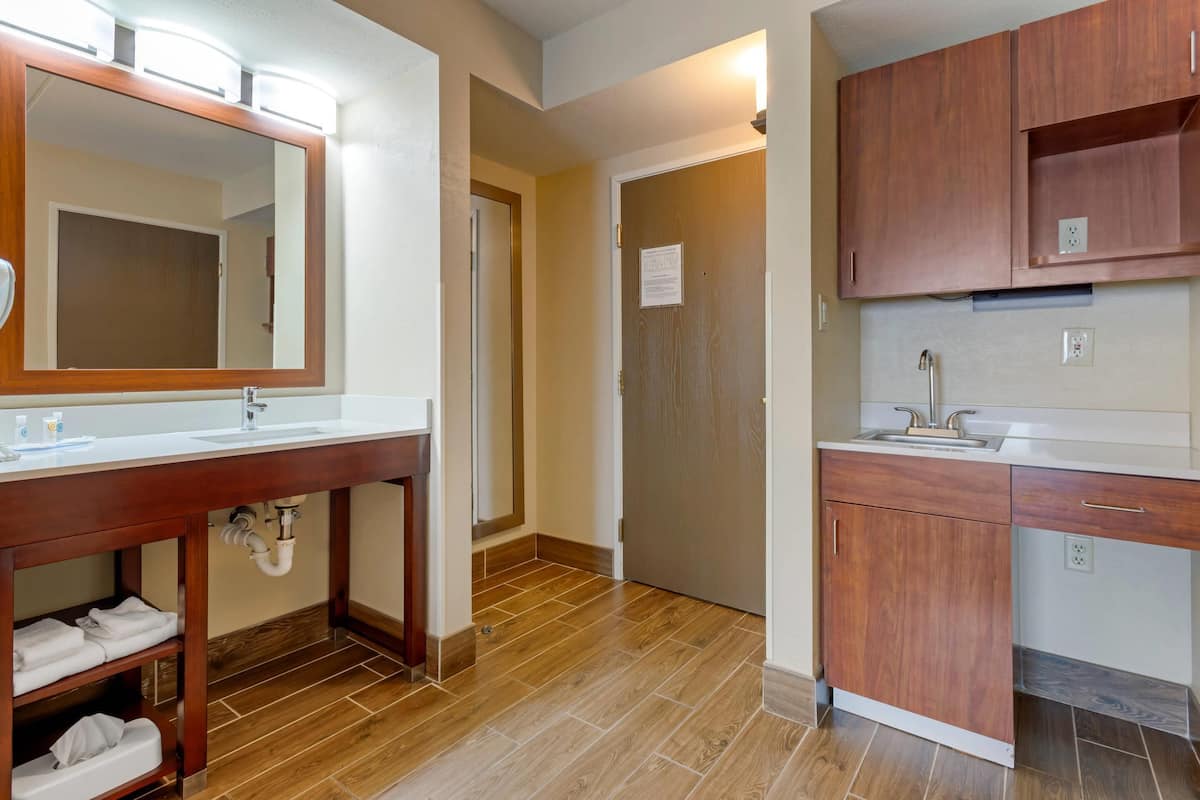A bathroom with a wooden vanity, a large mirror, and a sink.