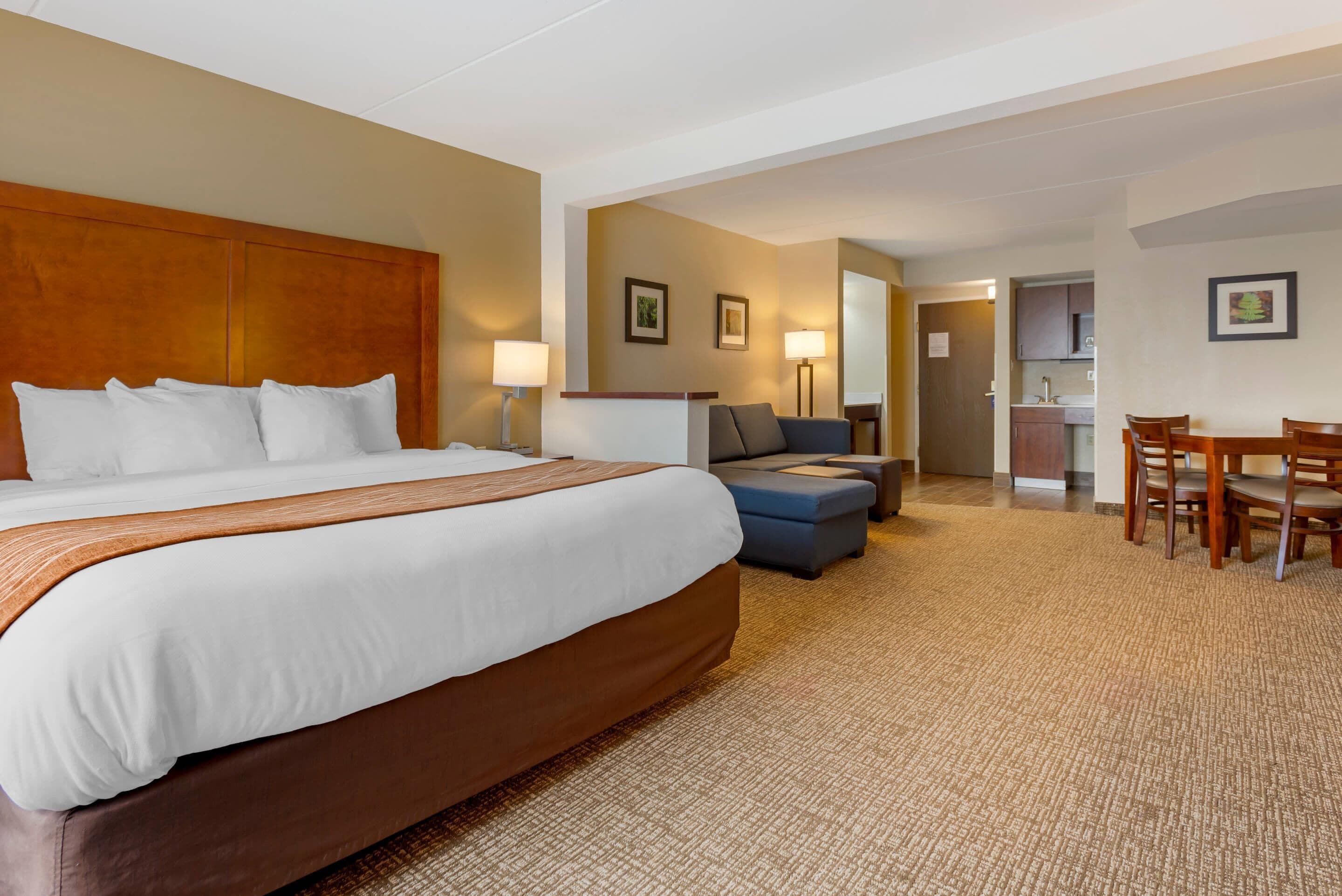 Una habitación de hotel con una cama grande, un sofá, una mesa de comedor y una kitchenette.