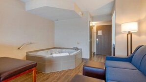 A modern bathroom with a large bathtub, a massage table, and a seating area with a lamp. - Comfort Inn & Suites Wilkes Barre - Arena (Wilkes-Barre)