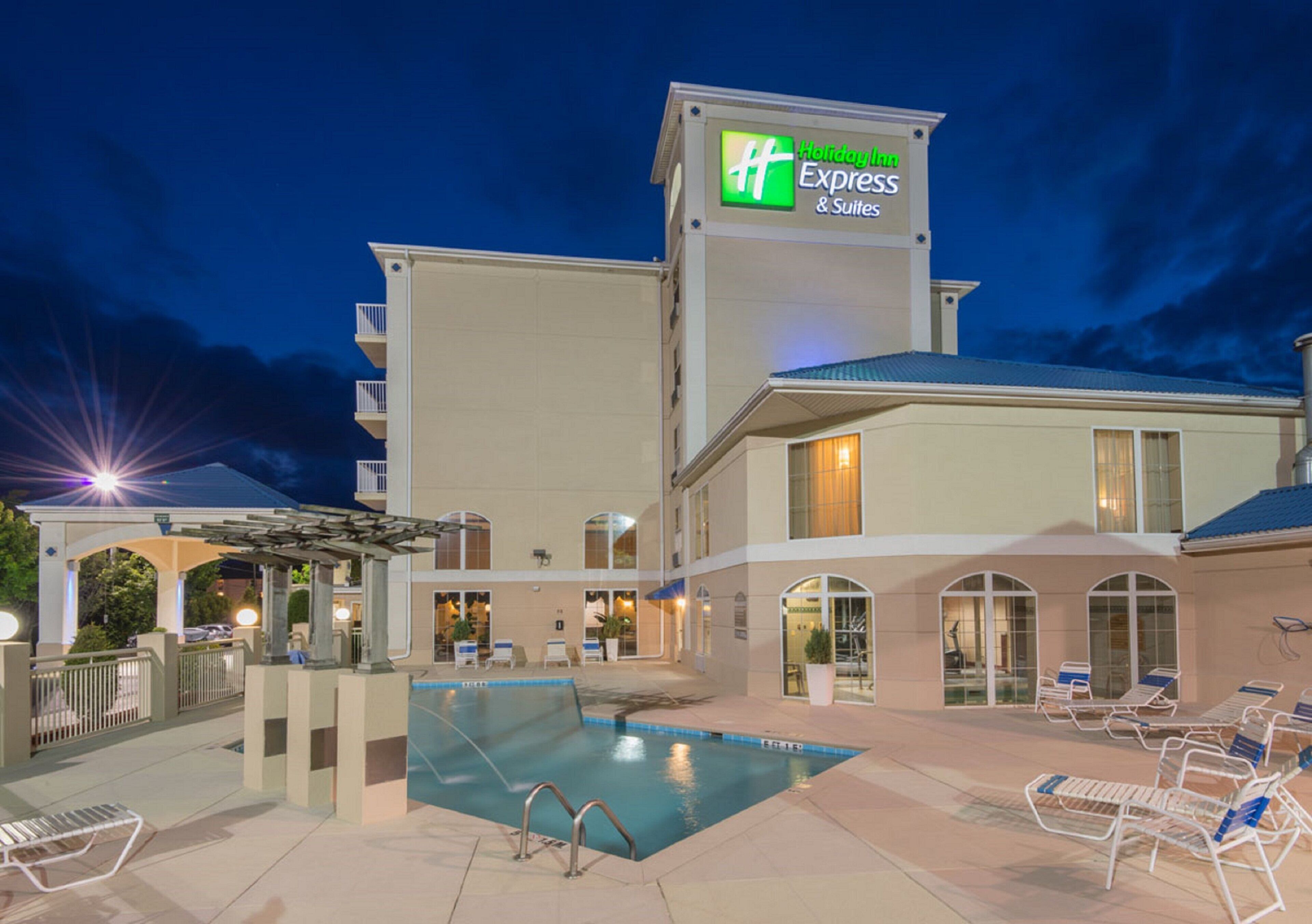 Ein Holiday Inn Express & Suites Gebäude mit Schwimmbecken und Liegestühlen.