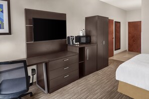 Ein Hotelzimmer mit Bett, Schreibtisch mit Stuhl, Fernseher, Mikrowelle und Kleiderschrank.