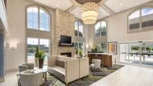 A spacious living area with a fireplace, comfortable seating, and large windows offering views of the outdoors. - Holiday Inn Express & Suites Asheville SW - Outlet Ctr Area by IHG (Asheville)