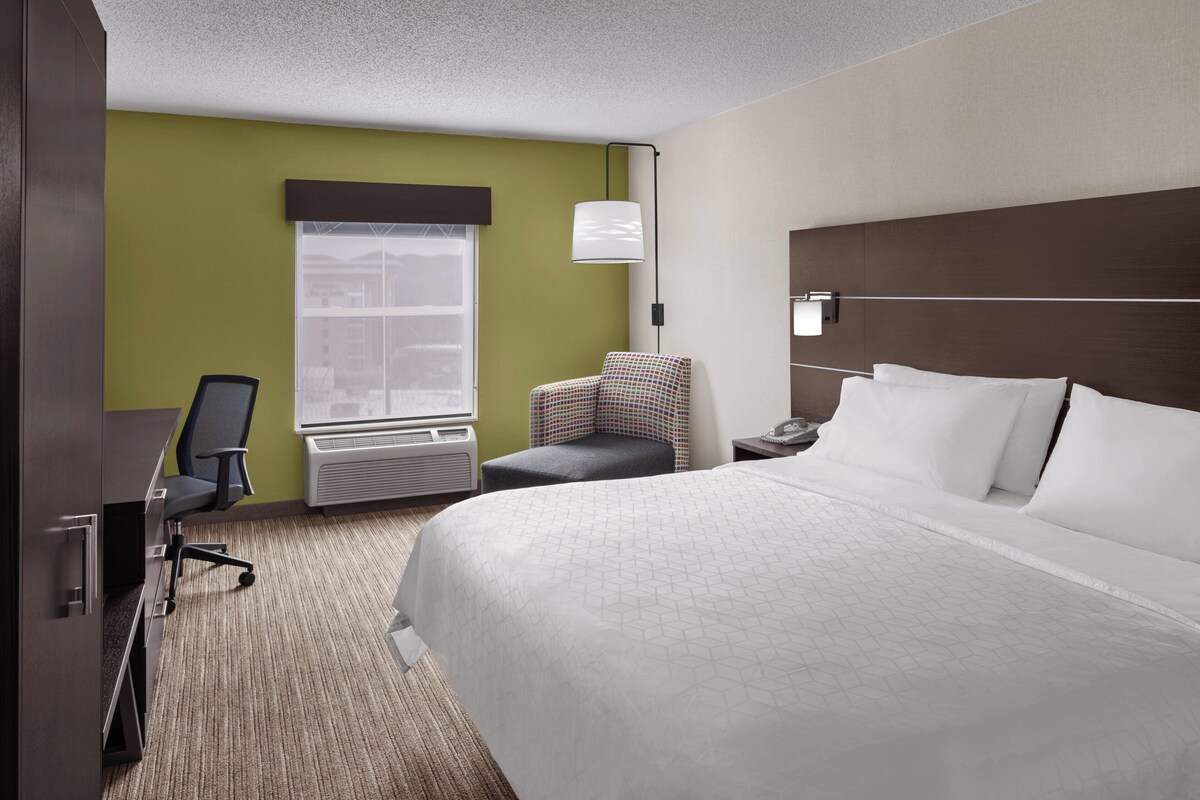 Ein Hotelzimmer mit Bett, Schreibtisch, Stuhl, Fenster und Nachttisch.