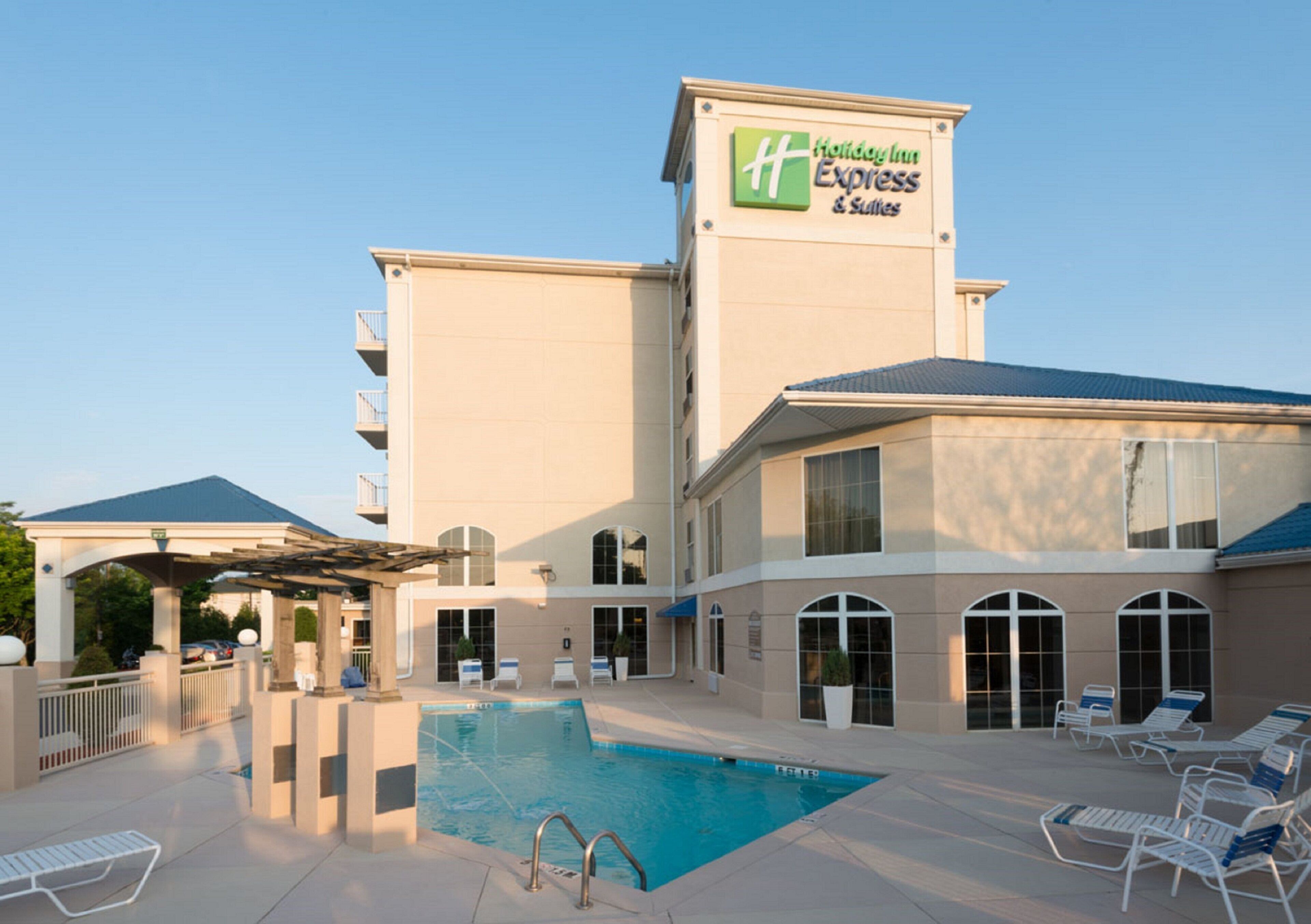 A Holiday Inn Express & Suites with a swimming pool and lounge chairs.