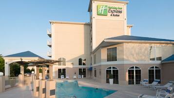 A Holiday Inn Express & Suites with a swimming pool and lounge chairs.