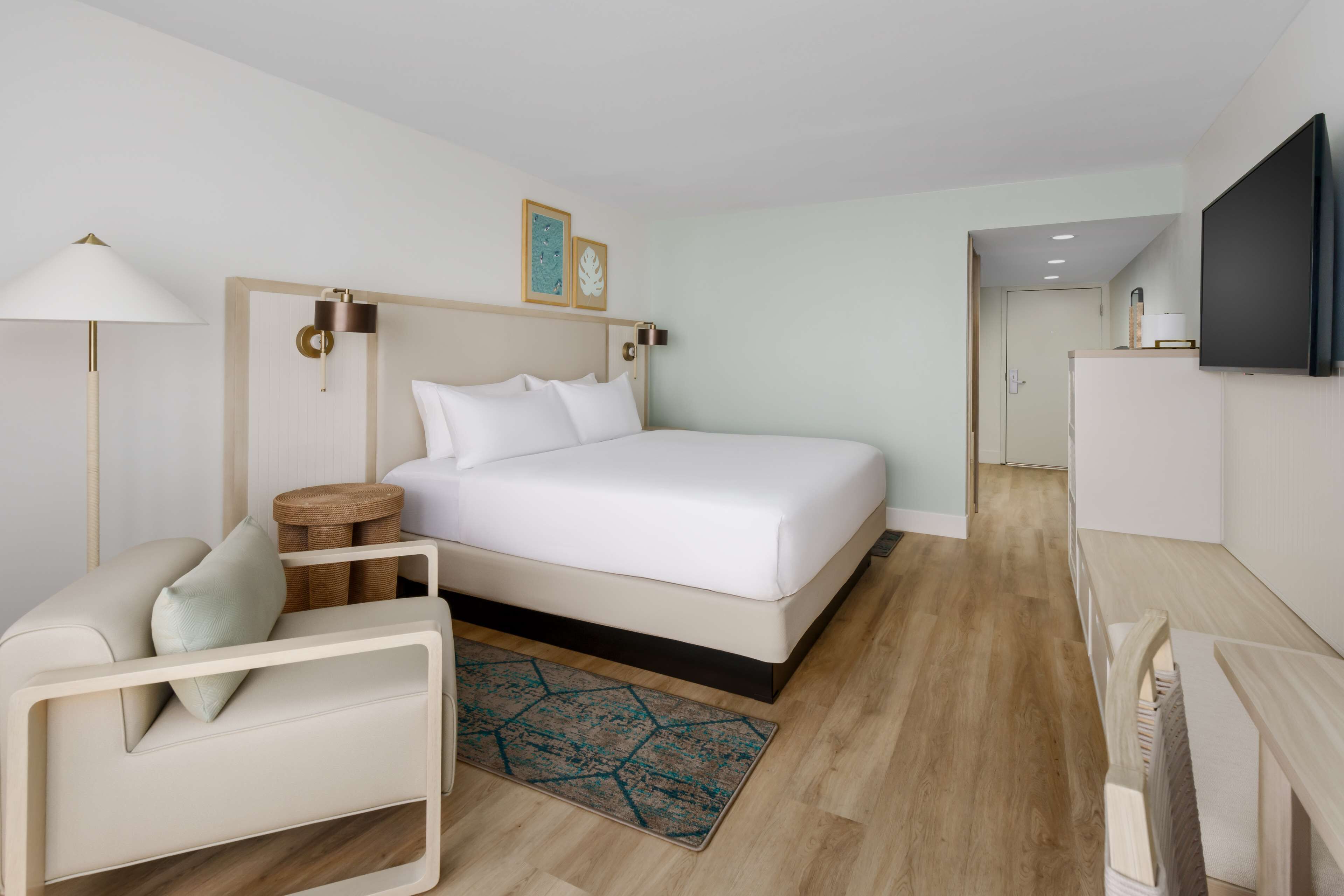 Een moderne hotelkamer met een groot bed, een bureau, een televisie en een klein nachtkastje.
